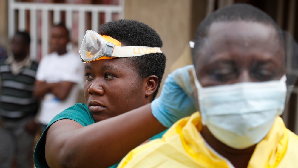Healthcare workers adjust gear before they enter a room where there is a baby suspected of dying of Ebola in Beni, North Kivu Province of the Democratic Republic of Congo, December 13, 2018 [Goran Tomasevic/Reuters]